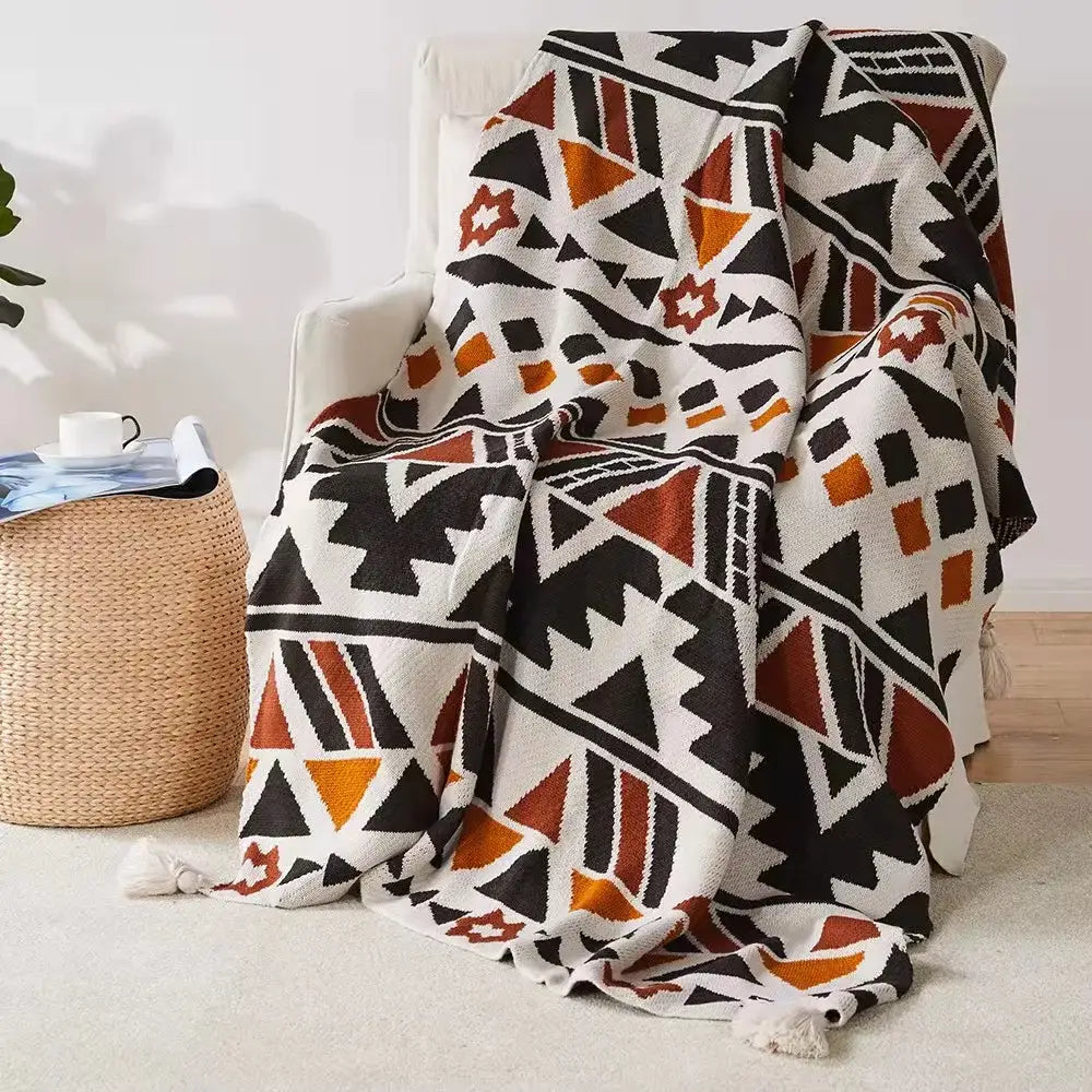 A cozy bohemian tassel knit blanket with bold black orange and white geometric pattern and tassels for decorbites decor