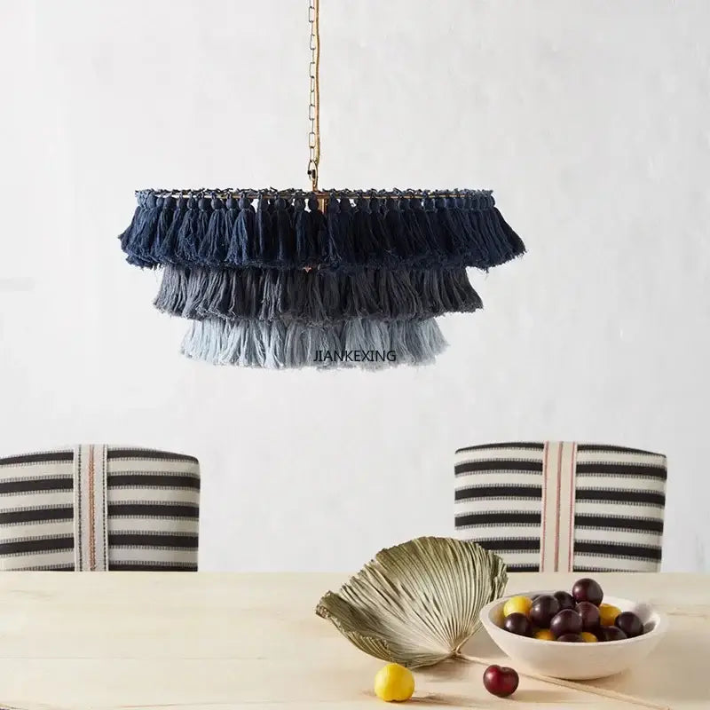 A bohemian vintage fela pendant light with cascading navy gray and light blue tassels hanging from a gold chain decorbites design
