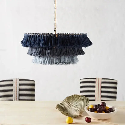 A bohemian vintage fela pendant light with cascading navy gray and light blue tassels hanging from a gold chain decorbites design