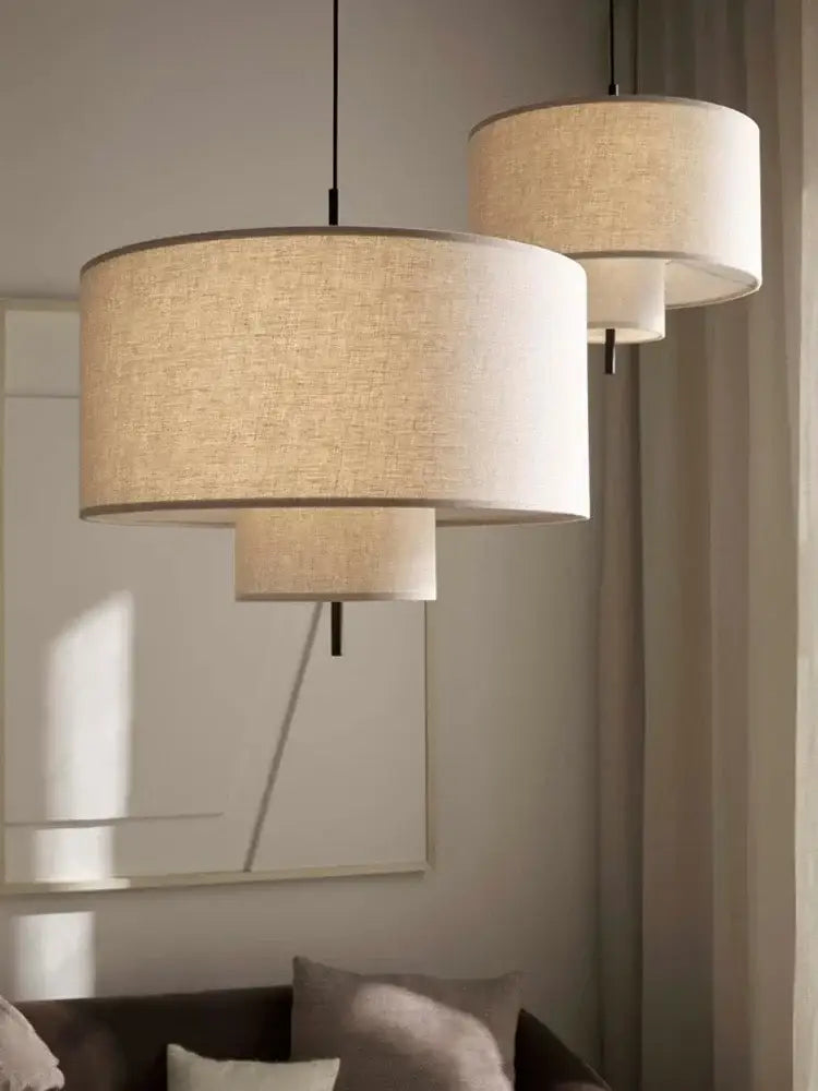 Beige cylindrical pendant lamps with textured linen shades and black cords decorbites bohemian wabi sabi decor