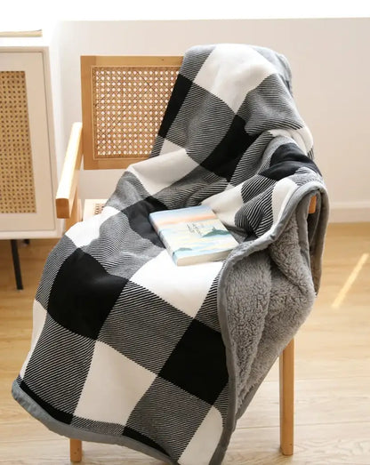 A cozy black and white plaid bohemian winter blanket with soft gray fleece lining for living room use