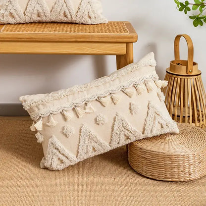 Cream-colored rectangular cushion cover with textured triangular patterns and tasseled trim in beige boho style decorbites
