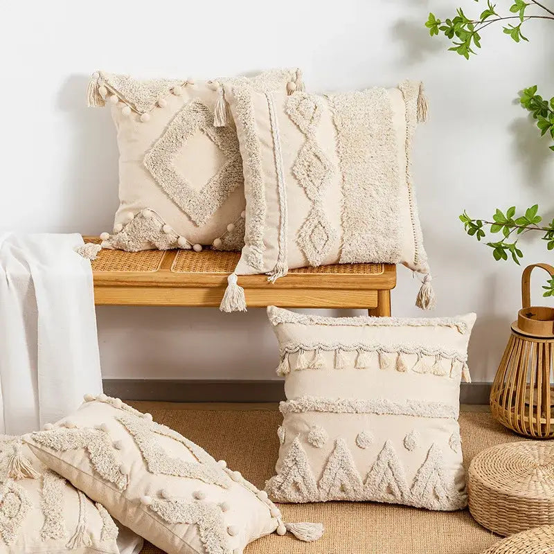 Cream-colored tufted fringed geometric pillow cover with tassels and pom-poms for boho living room decor