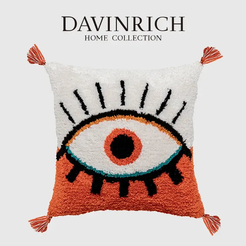 A plush boho big eye tufted cushion cover with black lashes and orange iris on white from decorbites boho big collection