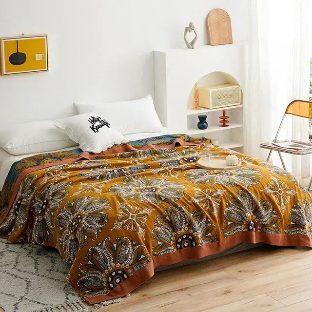 A cozy mustard yellow decorbites boho cotton blanket with brown and black floral patterns draped over a bed