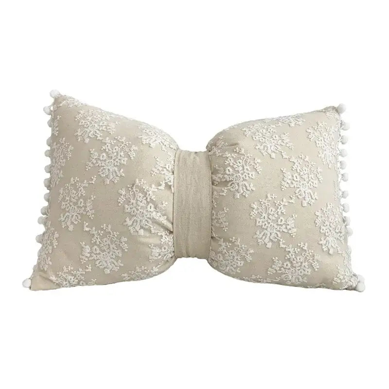 Beige bow-shaped cushion cover with white lace floral embroidery and pom-pom trim decorbites boho white style