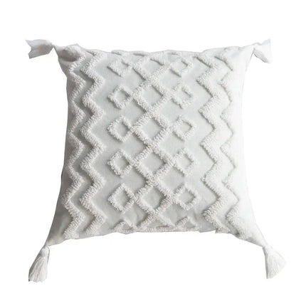 Boho cream textured pillow cover set featuring a white square pillow with diamond pattern and tassels at each corner