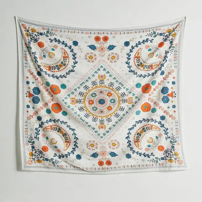 A square white embroidered wall tapestry featuring vibrant orange and blue flowers crescent moons and geometric designs for boho floral celestial decorbites decor