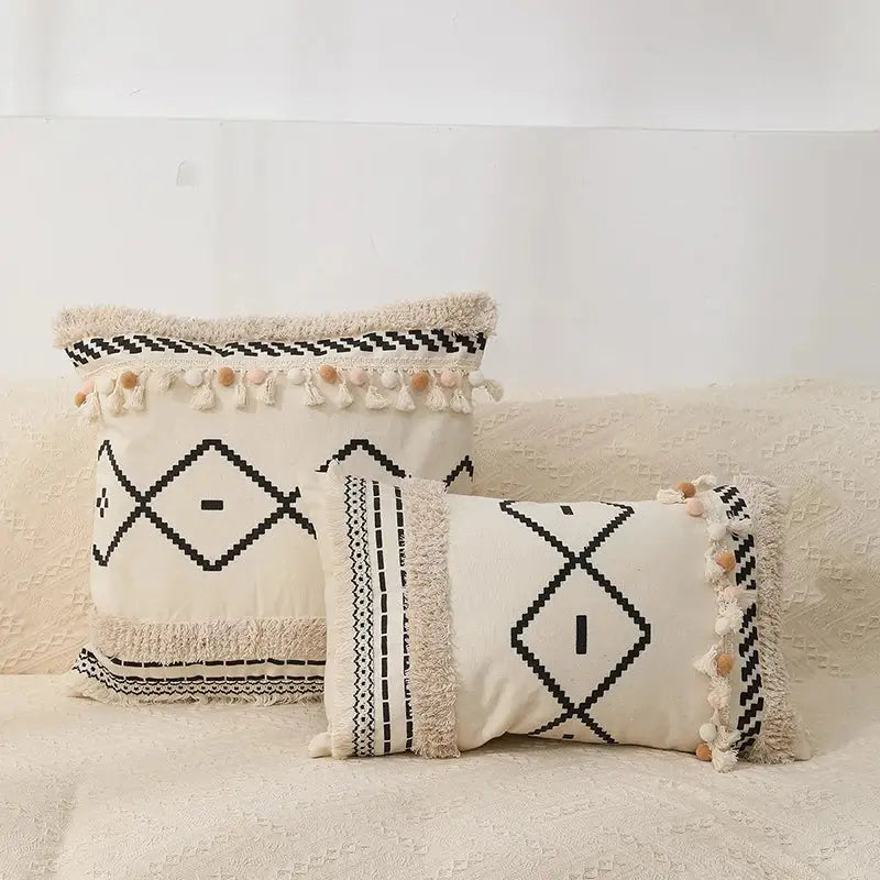 Cream-colored boho geometric chenille embroidered pillow covers with black patterns and tassel fringed edges for living room decorbites