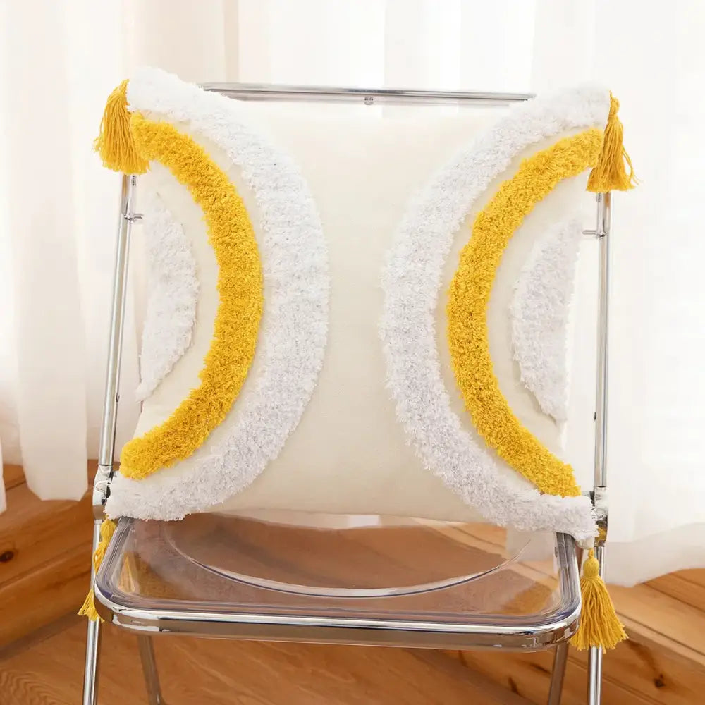 A cozy cream-colored cushion cover with tufted embroidery and yellow white tassel-trimmed geometric arches decorbites design