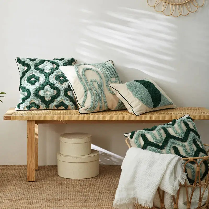 Three textured green and cream cushion covers with embroidered geometric patterns on a woven bench for decorbites blue tufted decor