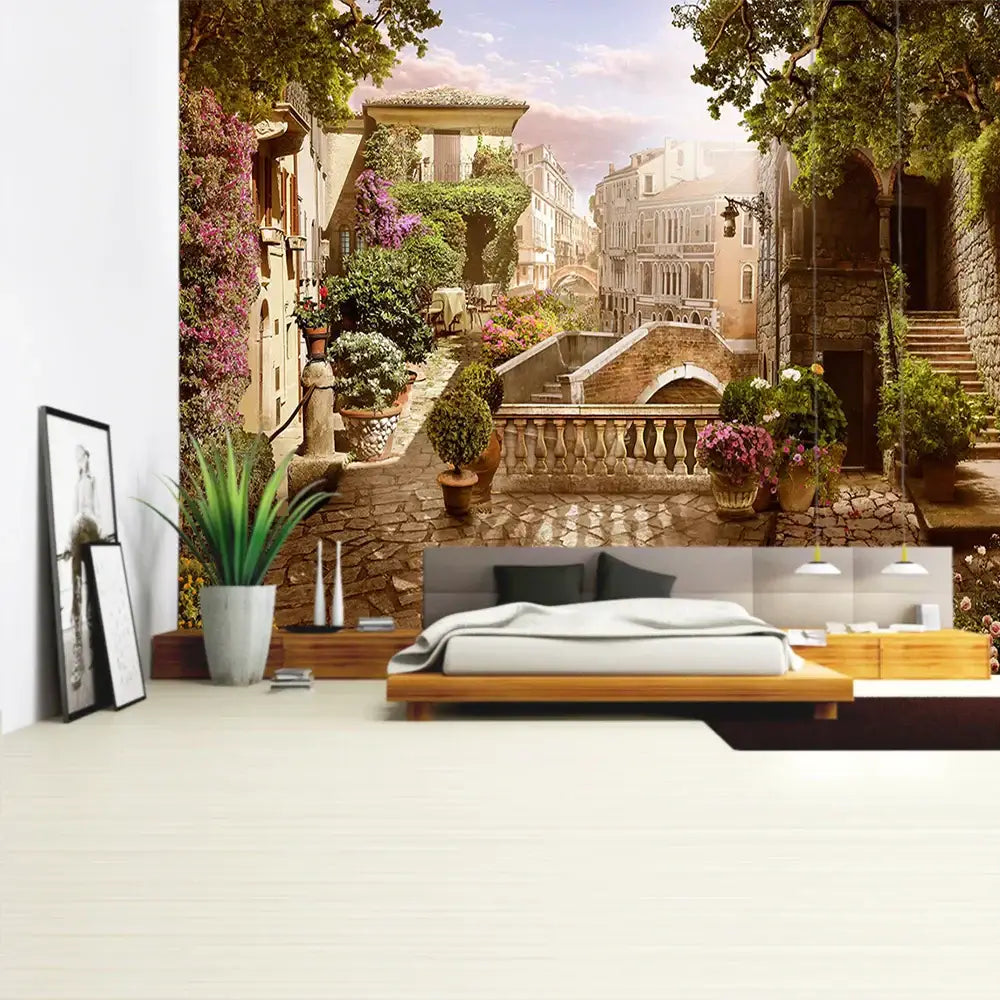 A boho bedroom features a decorbites green plant landscape tapestry of a sunlit italian village alleyway