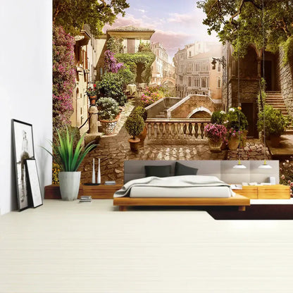 A boho bedroom features a decorbites green plant landscape tapestry of a sunlit italian village alleyway