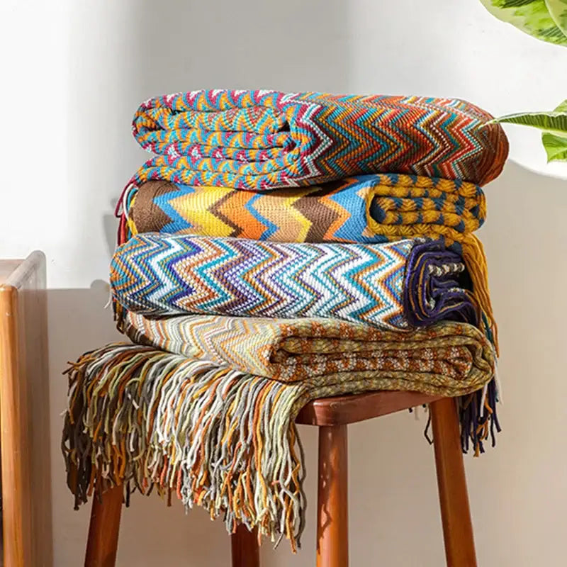 Stack of colorful boho knitted striped throws with zigzag pattern and fringed edges for living room decorbites decor