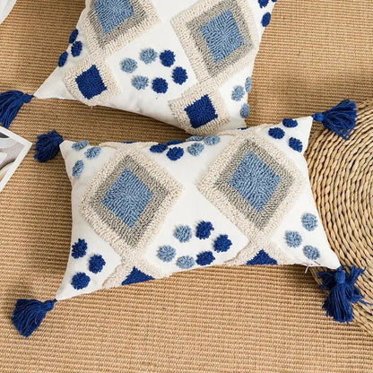 White rectangular pillow cover with blue and gray embroidered geometric patterns and navy tassels by decorbites boho loop tufted