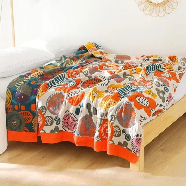 A vibrant boho mandala cotton summer blanket with bold orange teal floral motifs and orange hem for decorbites throw