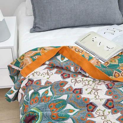 A cozy boho mandala cotton summer blanket with vibrant teal orange peacock feather pattern on cream background
