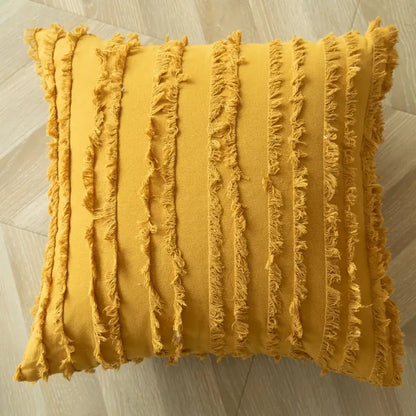 A square mustard yellow cushion cover with vertical frayed stripes and a decorbites geometric tufted embroidered design