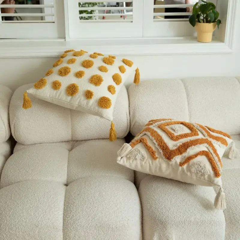 Cream-colored cushion cover with mustard yellow tassels and geometric tufted embroidered patterns for boho decorbites decor