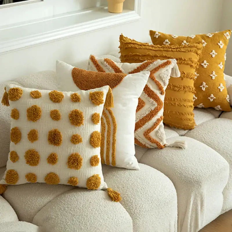 Cream-colored cushion cover with mustard pom-poms and textured cotton fabric for decorbites geometric tufted decor