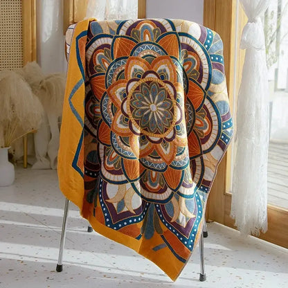 A vibrant orange and blue mandala-patterned boho patchwork cotton gauze bath towel draped over a metal chair