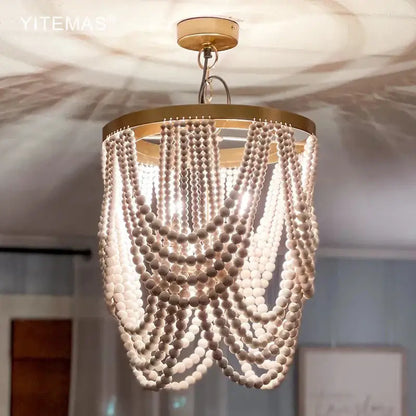 Boho tiered wooden beaded chandelier with white beads and gold-toned frame for dining room lighting