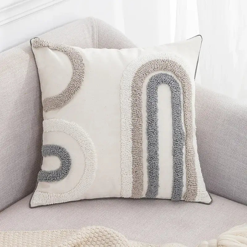 A cozy cream cushion cover with a boho tufted embroidered rainbow design in soft grey and beige tones for living room decor