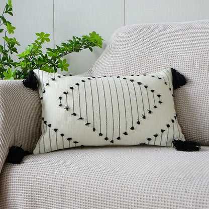 Cream-colored rectangular boho tufted fringed pillowcase with black vertical stripes and tassel accents for living room decor