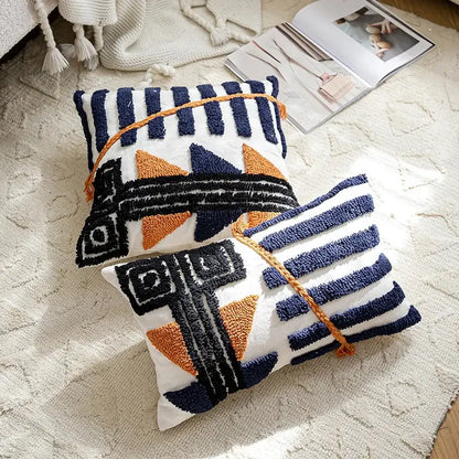 Two rectangular decorbites boho tufted pillow covers with navy and burnt orange geometric patterns tied with braided cord