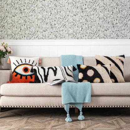 A cozy beige sofa with colorful throw pillows and a boho white and black decorbites black abstract eye pillow cover