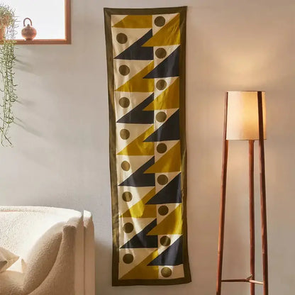 A long narrow silk scarf with bold yellow triangles and black circles celestial geometry tapestry design