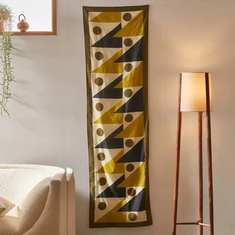 A long narrow silk scarf with bold yellow triangles and black circles celestial geometry tapestry design