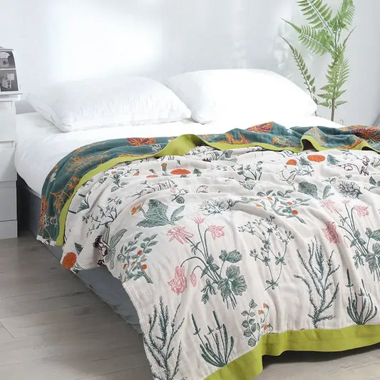 A soft off-white decorbites cotton leisure blanket with delicate pink and green botanical print and lime-green border