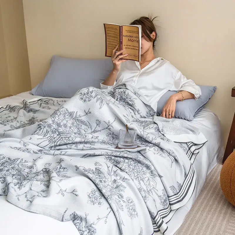 A soft white and gray floral summer quilt made from bamboo four layer fabric draped over a bed for decorbites bamboo four