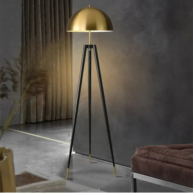 A sleek brass and black decorbites coyote gold tripod floor lamp with a polished dome shade for living room decor