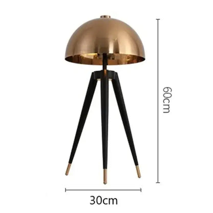 A sleek brass and black floor lamp with decorbites coyote gold tripod legs and gold-tipped feet, 60cm tall