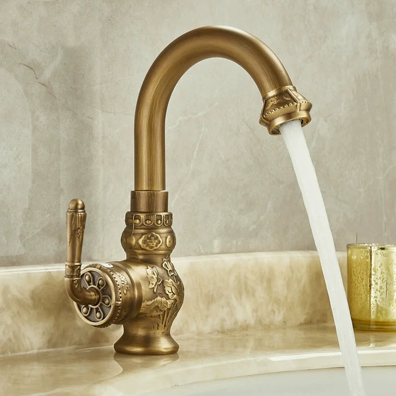 Brass antique bathroom sink faucet with antique brass finish and ornate floral and scrollwork detailing on spout handle and base
