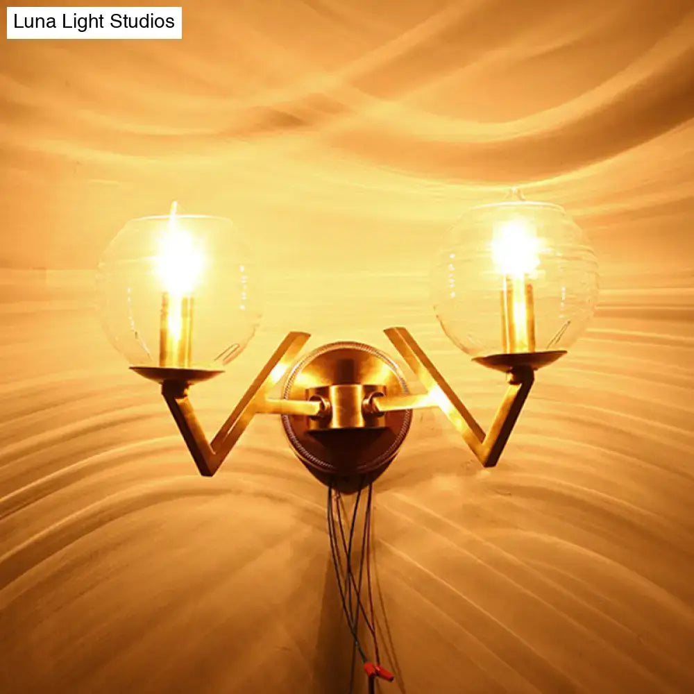 Brass ball sconce with ribbed glass shade featuring two spherical glass shades and candle-style bulbs for bedroom wall lighting
