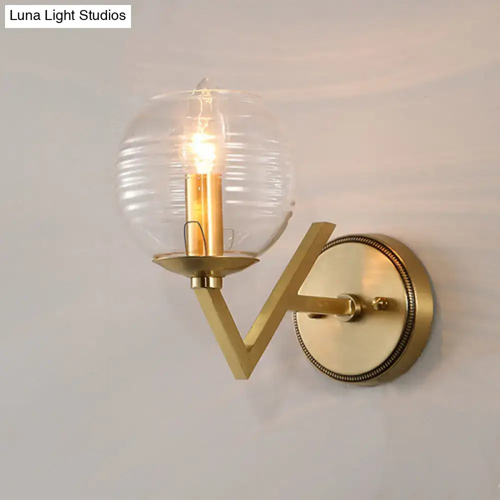 Brass ball sconce with ribbed glass shade and exposed filament bulb for bedroom wall lighting