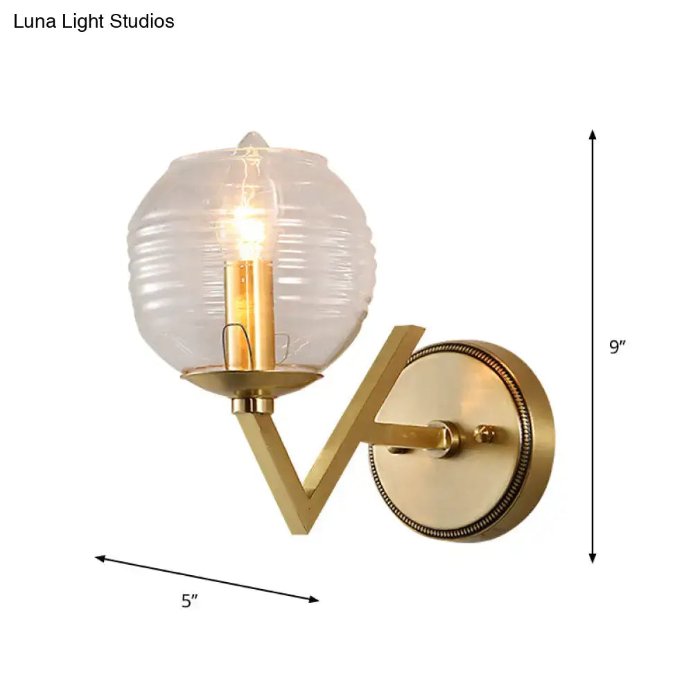 Brass ball sconce with gold-toned ribbed glass shade and exposed filament bulb for bedroom wall lighting
