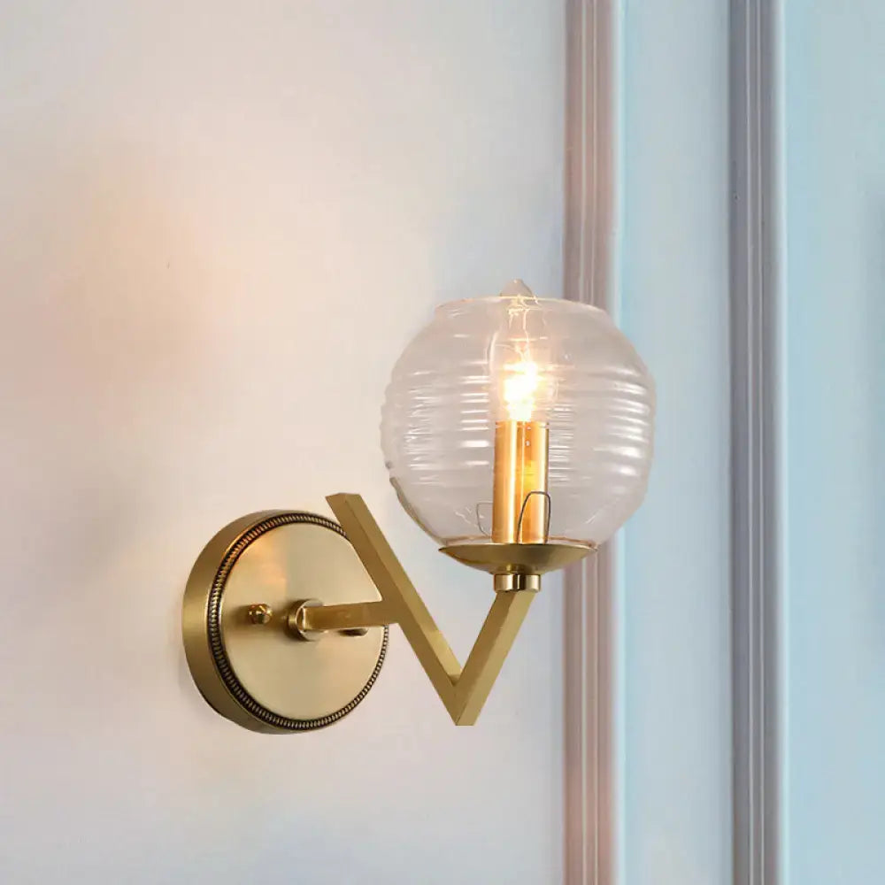 Brass ball sconce with ribbed glass shade and exposed filament bulb for bedroom wall lighting