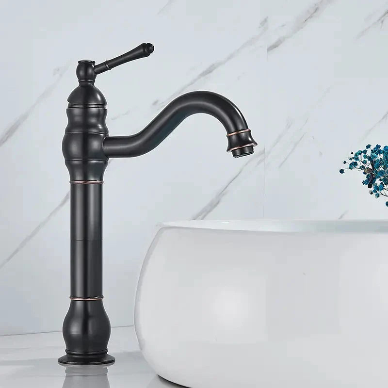 Brass bathroom basin mixer faucet with black matte finish, curved spout, ornate handle, and subtle copper accents