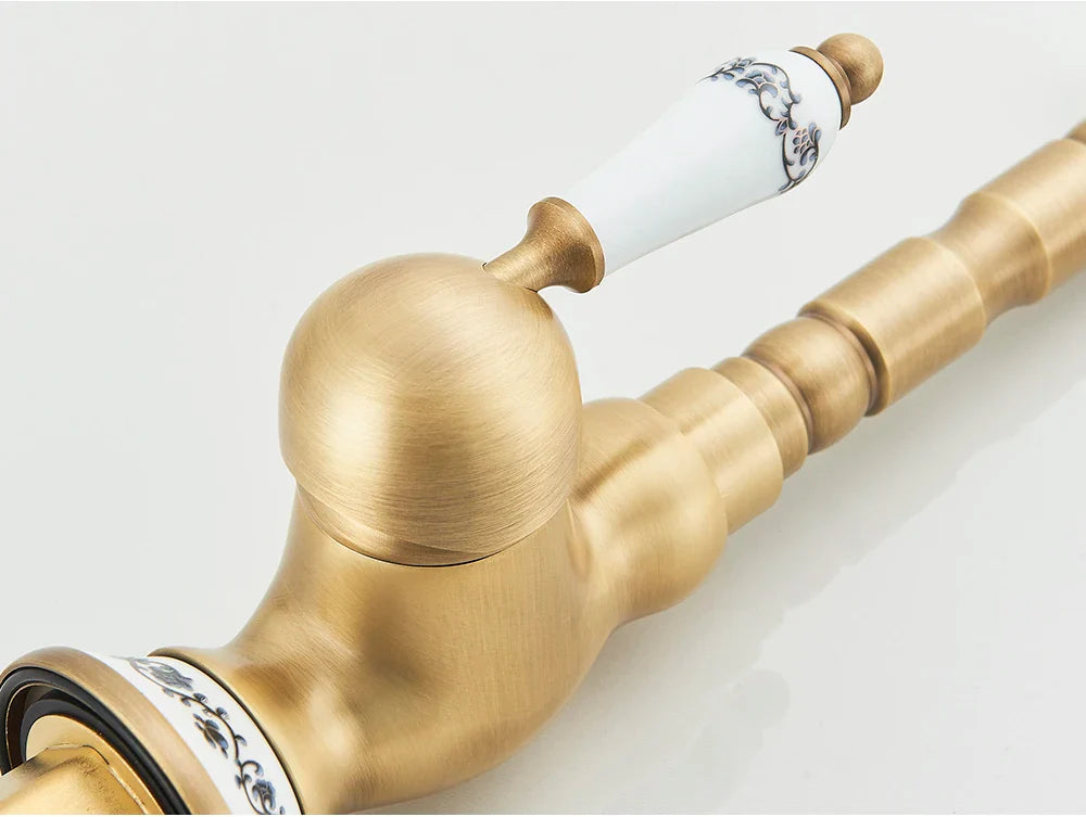 Antique brass-finished deck mounted kitchen faucet with rotating neck and white ceramic handle with black floral patterns