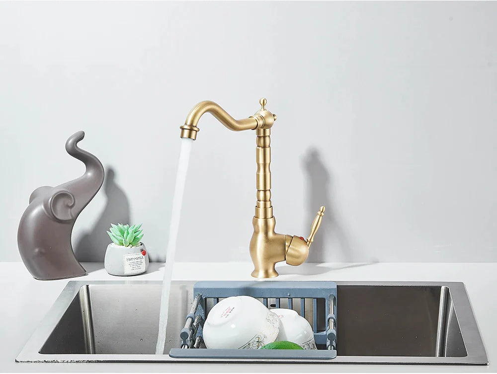 Brass kitchen faucet deck mounted with rotating neck, curved spout, and ornate segmented brass finish design