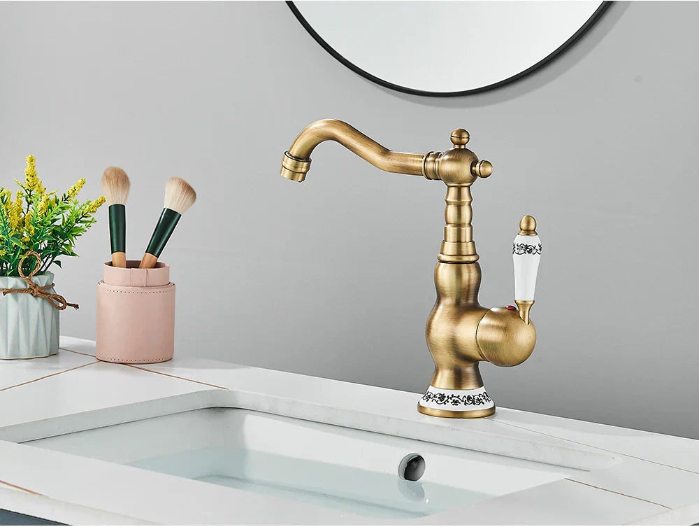 Deck mounted brass kitchen faucet with antique brass finish ornate detailing and white ceramic handles with black floral engraving