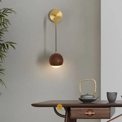 Gold-toned wall lamp with spherical walnut wood shade brass led walnut wood decorbites bedroom sconce