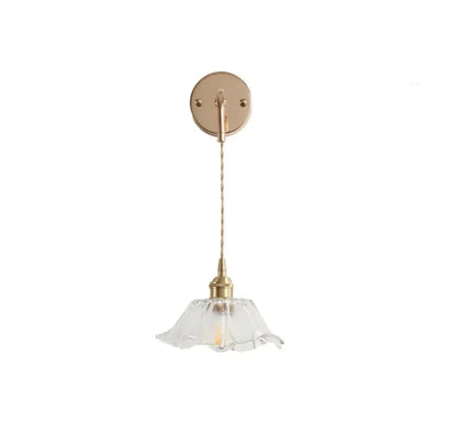A brass petal glass decorbites adjustable led wall light with clear glass shade and twisted cord for bedroom use