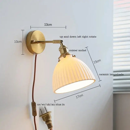 Brass ribbed decorbites ceramic wall sconce with iron arm featuring brass finish and off-white ribbed ceramic shade