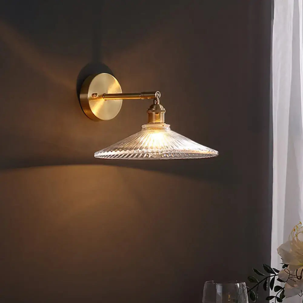 Brass scalloped glass shade bedside sconce light fixture with a brass finish and clear ribbed glass shade