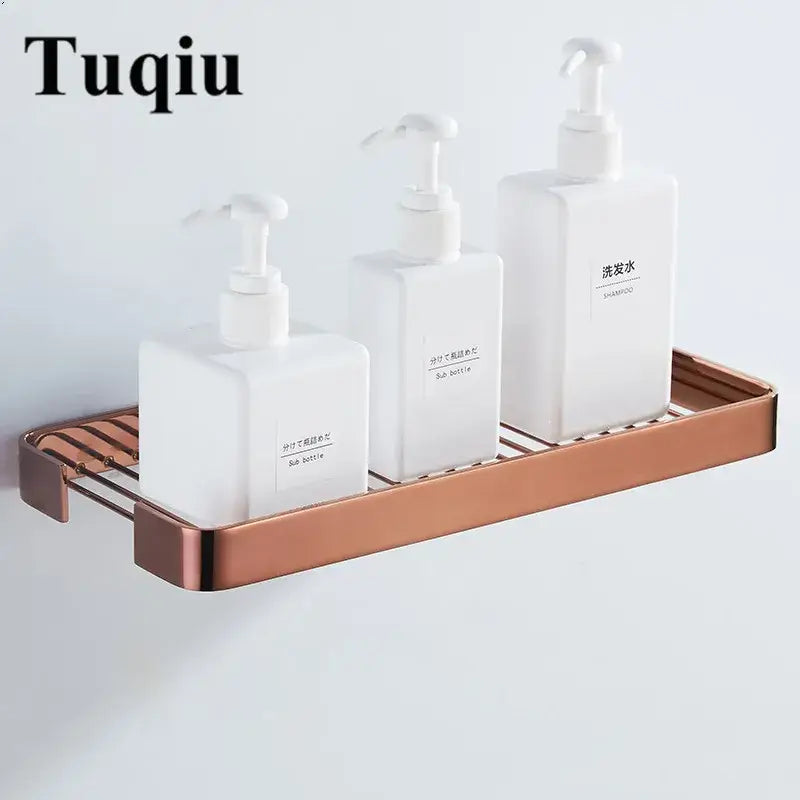 Brass square bathroom shower rack copper-toned metal wall-mounted slatted shelf holding three white pump bottles